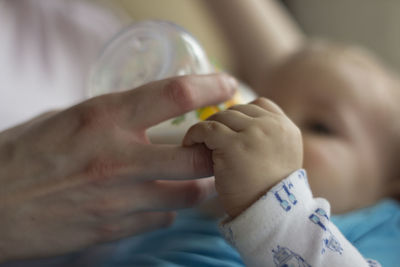 Cropped hand of mother feeding baby from milk bottle