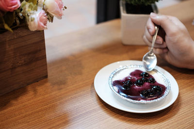 Close-up of hand with ice cream in plate on table