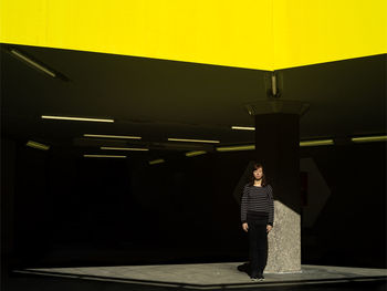 Woman standing against illuminated wall