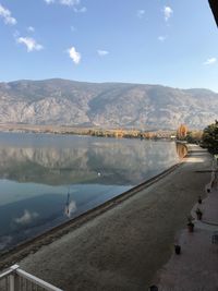 Woman looking at lake by mountains against sky