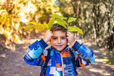 Little kid playing with leaves in autumn