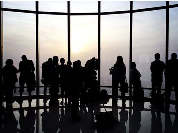 Silhouette people against glass window at burj khalifa