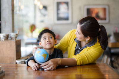 Mother and son with globe sitting at desk