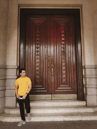 Portrait of man standing against door of building