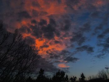 Low angle view of silhouette trees against dramatic sky