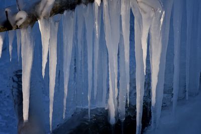 Icicles on snow covered landscape against sky