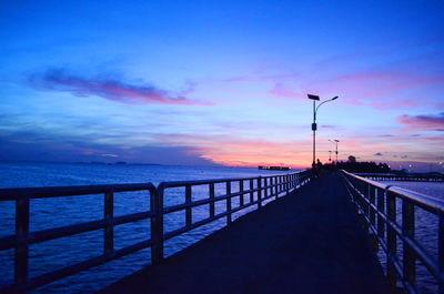 Street by sea against sky during sunset