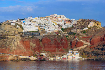 Buildings by sea against sky