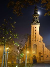 Low angle view of illuminated street light by building at night