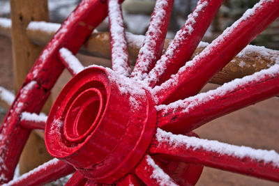 Close-up of snow on red wagon wheel