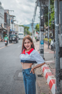 Portrait of smiling young woman standing on street in city