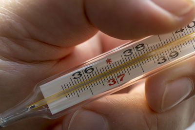 Close-up of human hand holding thermometer