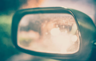 Reflection of man photographing on side-view mirror