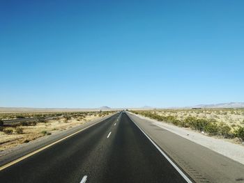 Road against clear blue sky