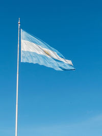 Low angle view of argentinian flag against blue sky