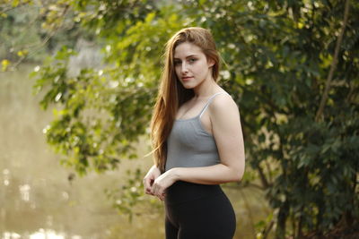 Young woman standing against trees