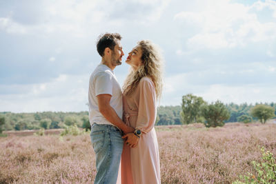 Young couple standing on field and looking to each other 