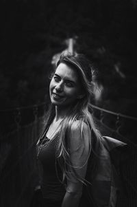 Portrait of smiling young woman standing on bridge