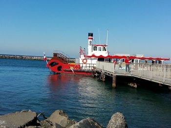 Ship moored in sea against clear blue sky