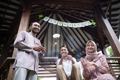 Portrait of smiling friends standing against wall