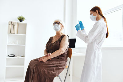 Doctor wearing mask vaccinating patient at hospital