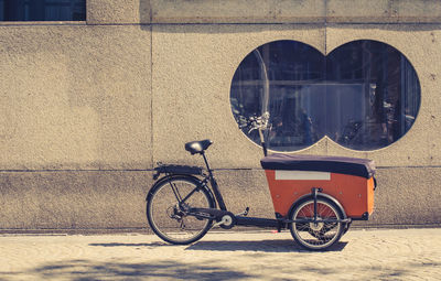 Cargo bicycle on sidewalk against wall