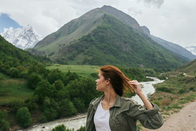 Young woman standing on mountain against sky