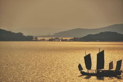 High angle view of silhouette sailing on sea at sunset