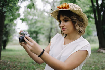 Woman taking selfie through camera against trees