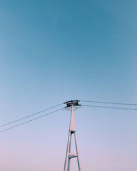 Low angle view of electricity pylon against clear sky