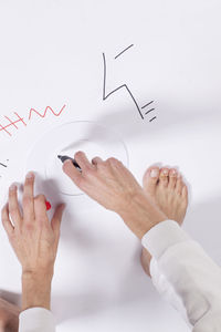 Low section of man holding hands over white background