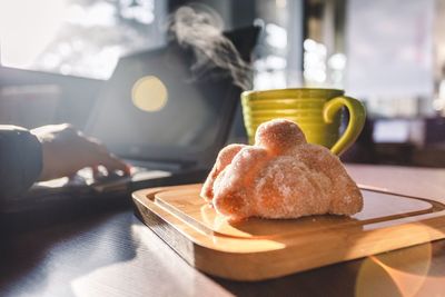 Cropped hand using laptop by food on table