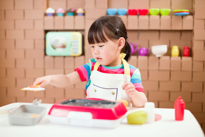 Portrait of cute girl with toy sitting on table