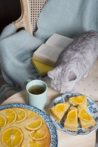 Gray kitten sits in an armchair with a orange pie and books, cozy vibes,