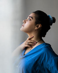 Young woman looking away against wall