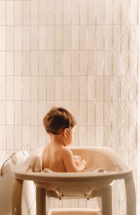 Portrait  of baby sitting in shower 