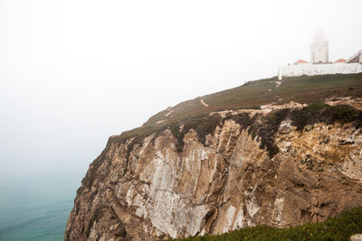 Scenic view of sea by mountain against clear sky