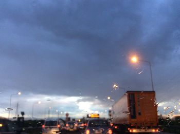 Low angle view of illuminated street light against cloudy sky