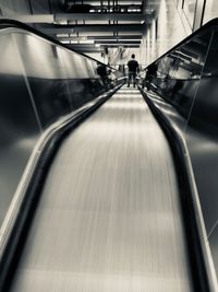 Rear view of people walking on escalator