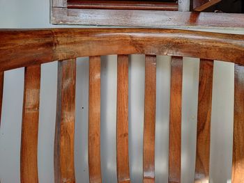 Close-up of wooden railing against wall