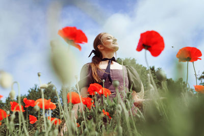 Portrait of young woman standing amidst flowers