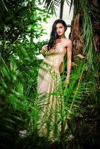 Portrait of young woman standing against tree