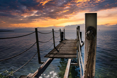 Pier over sea against sky during sunset