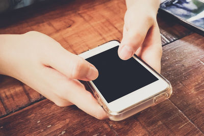 Close-up of woman hand using mobile phone on table