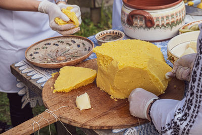 Woman's hands cut polenta on the table with romanian ornaments