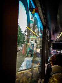 Reflection of illuminated building in mirror against sky seen through window