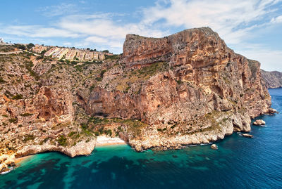 Rock formations by sea against sky