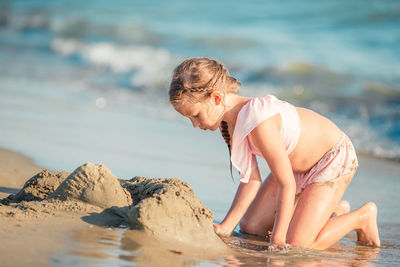 Side view of young woman sitting at beach