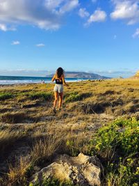 Rear view of woman running towards sea 
