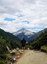 Rear view of man standing on mountain against sky
